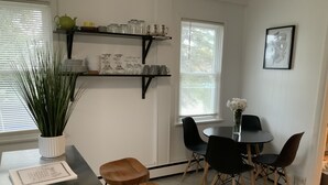 A modern kitchen with a dining area, featuring a black table, wooden stools, and a potted plant. - Lilly’s Place is cozy and relaxing every room has it’s own unique style. (Glasco)