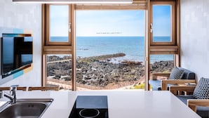 A modern kitchen with a large window overlooking a rocky coastline. - Jeju Ollero (Jeju City)
