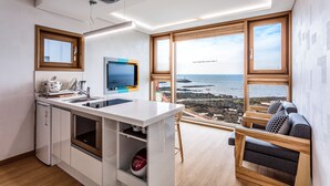 A modern kitchen with a built-in oven, a microwave, and a sink. There is a large window offering a view of the sea. - Jeju Ollero (Jeju City)