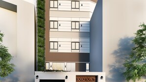 Een modern gebouw met een glazen balkon, een etalage met een zichtbaar logo, en een rode sportauto die ervoor geparkeerd staat.