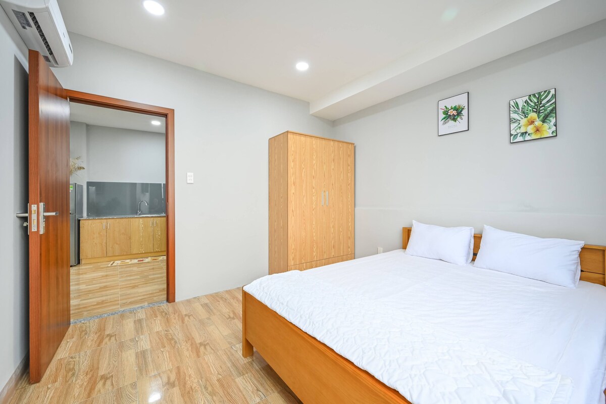 Een slaapkamer met een houten bed, een kledingkast en een badkamer zichtbaar door een open deur.