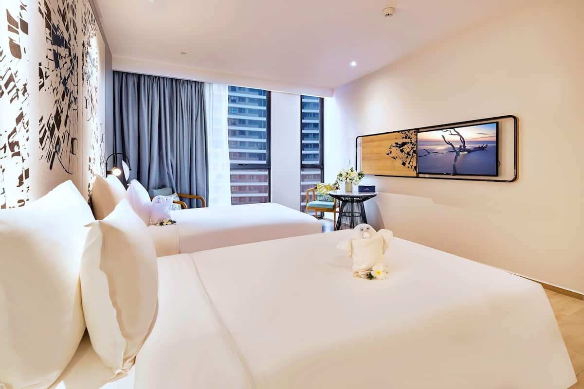 Ein Hotelzimmer mit zwei Betten, einem Schreibtisch und einem großen Fenster mit Vorhängen.