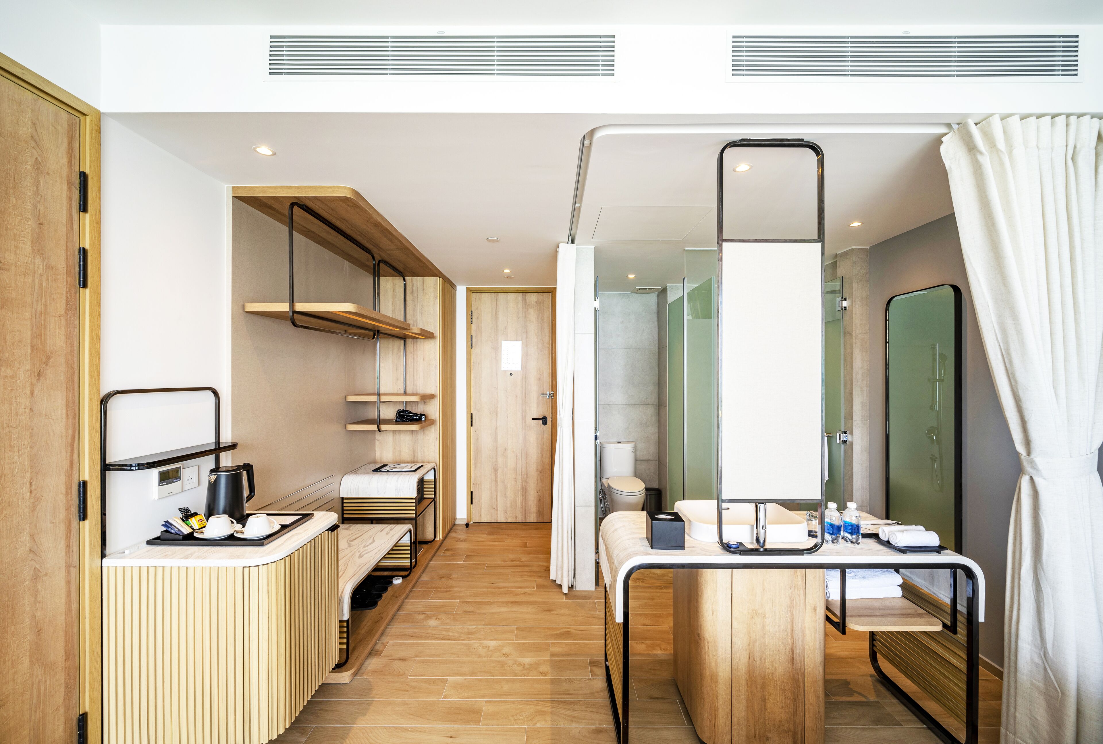 A compact hotel room with a kitchenette, a shower area, and a bed.