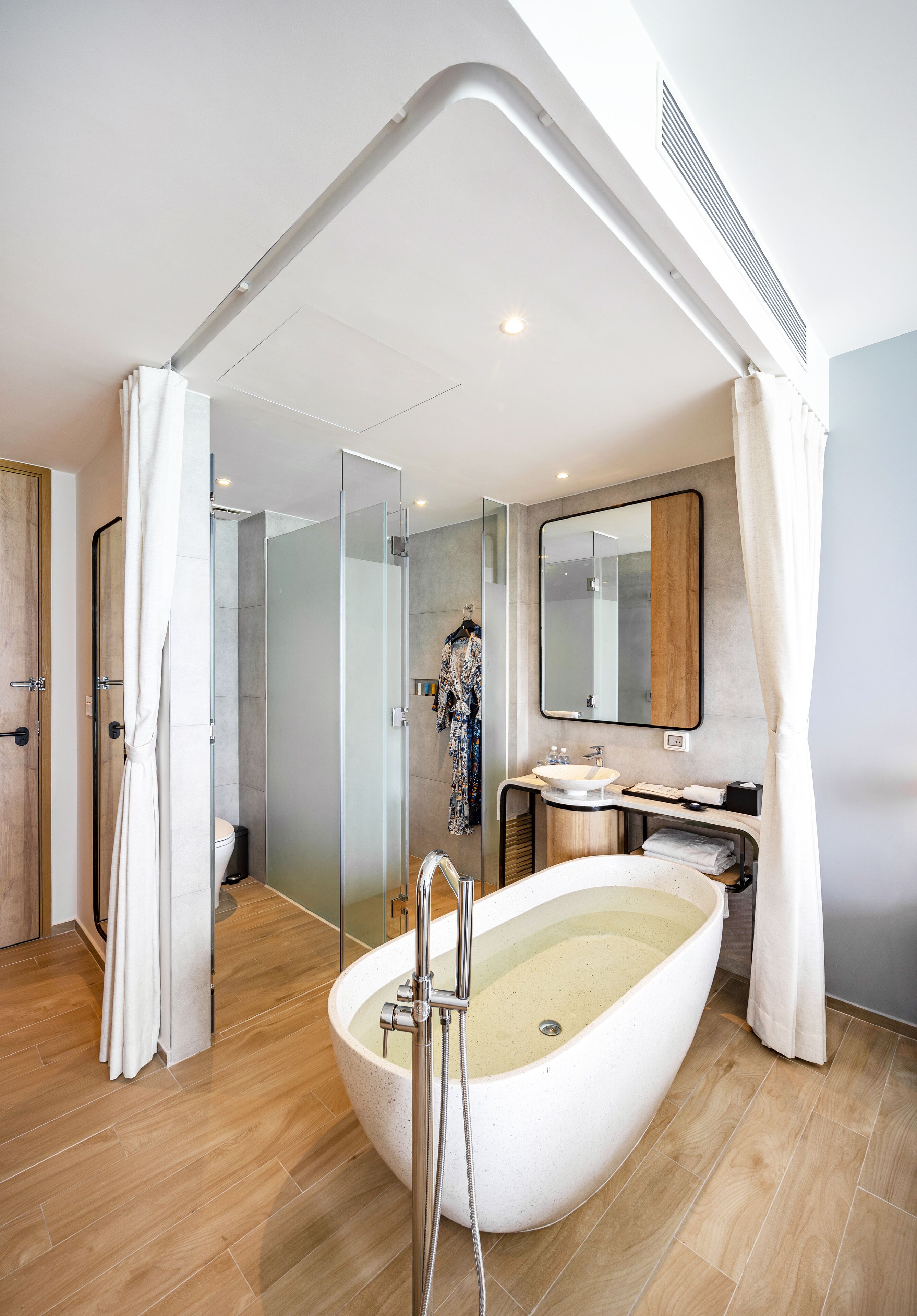A modern bathroom with a freestanding bathtub, glass shower enclosure, and a vanity with a mirror.