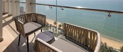 A balcony with wicker furniture and a view of the beach.