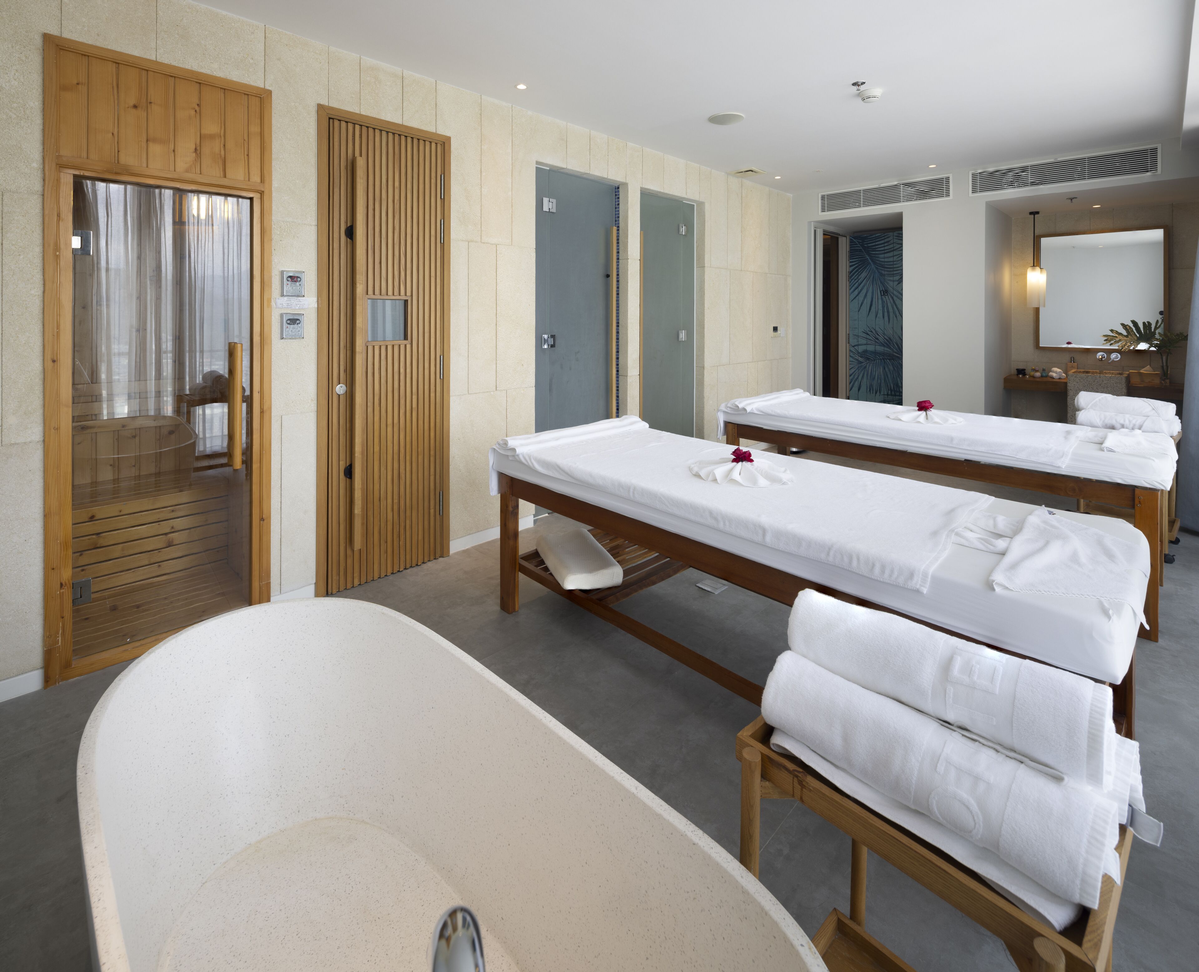 A hotel room with two wooden beds, a large bathtub, and a wooden wardrobe.