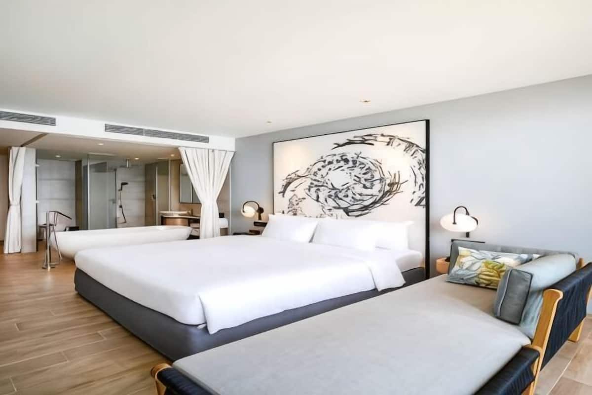 Ein modernes Hotelzimmer mit einem großen Bett, einem kleineren Bett, einer Sitzecke und einem großen, abstrakten Kunstwerk an der Wand.