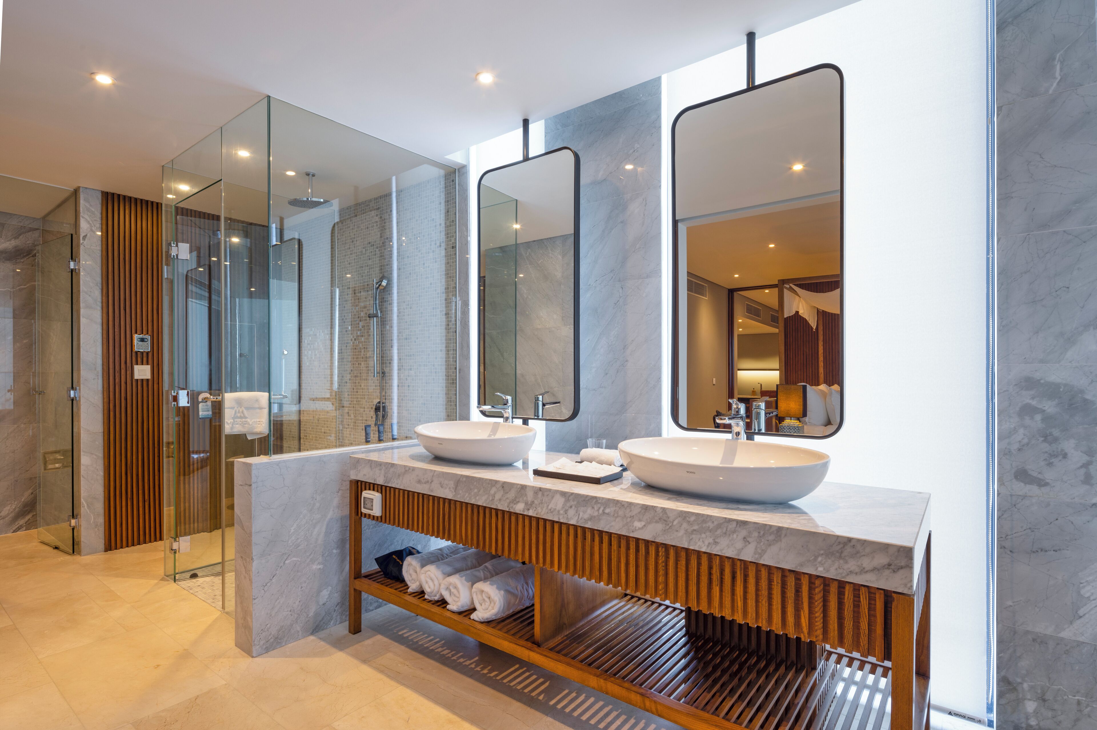 Une salle de bain moderne avec deux lavabos, de grands miroirs et une douche à l’italienne en verre.