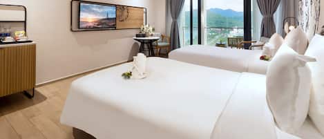 A hotel room with two beds, a desk, a chair, and a large window with a view.