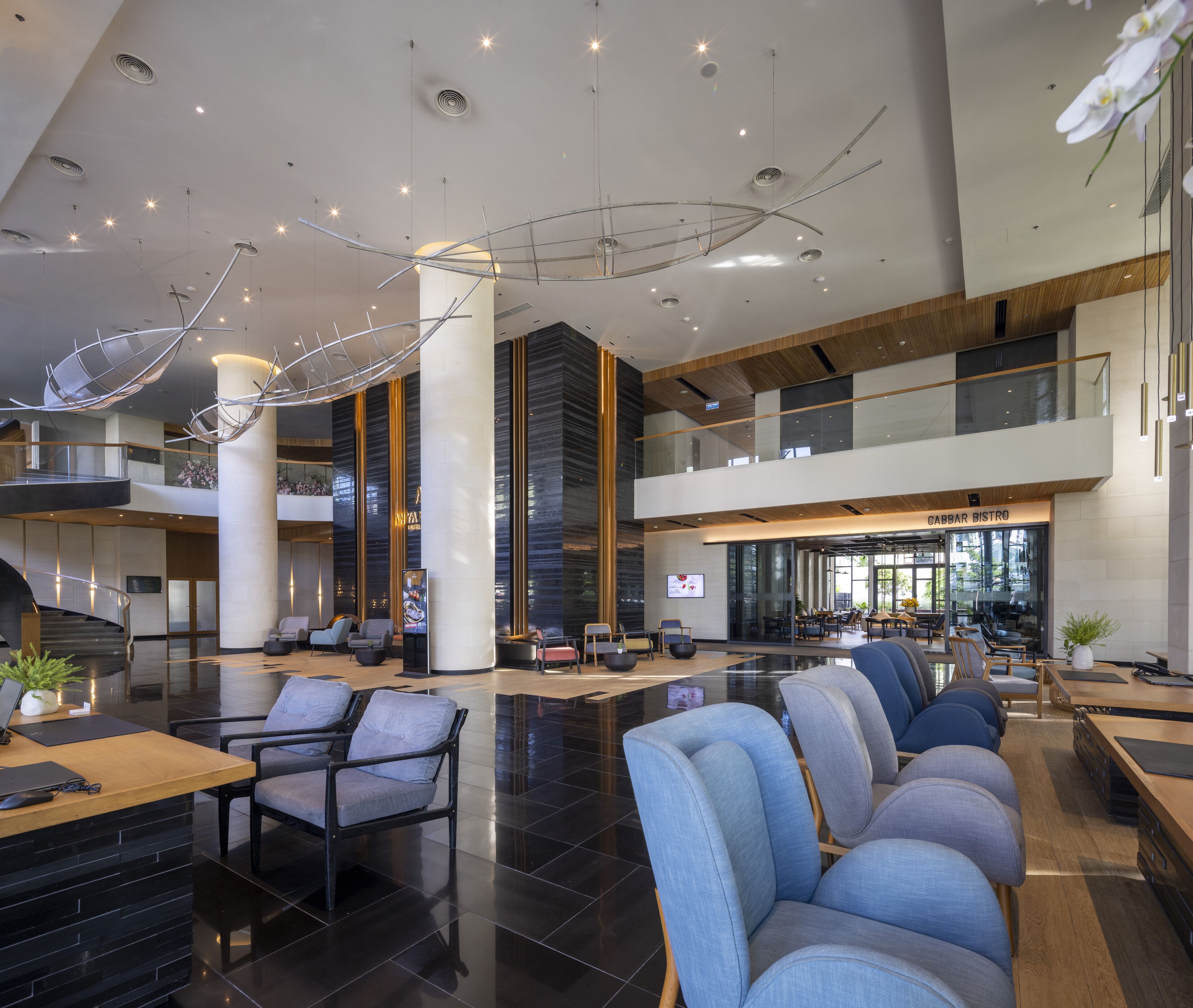 A spacious lobby with modern furniture, a staircase, and a dining area.