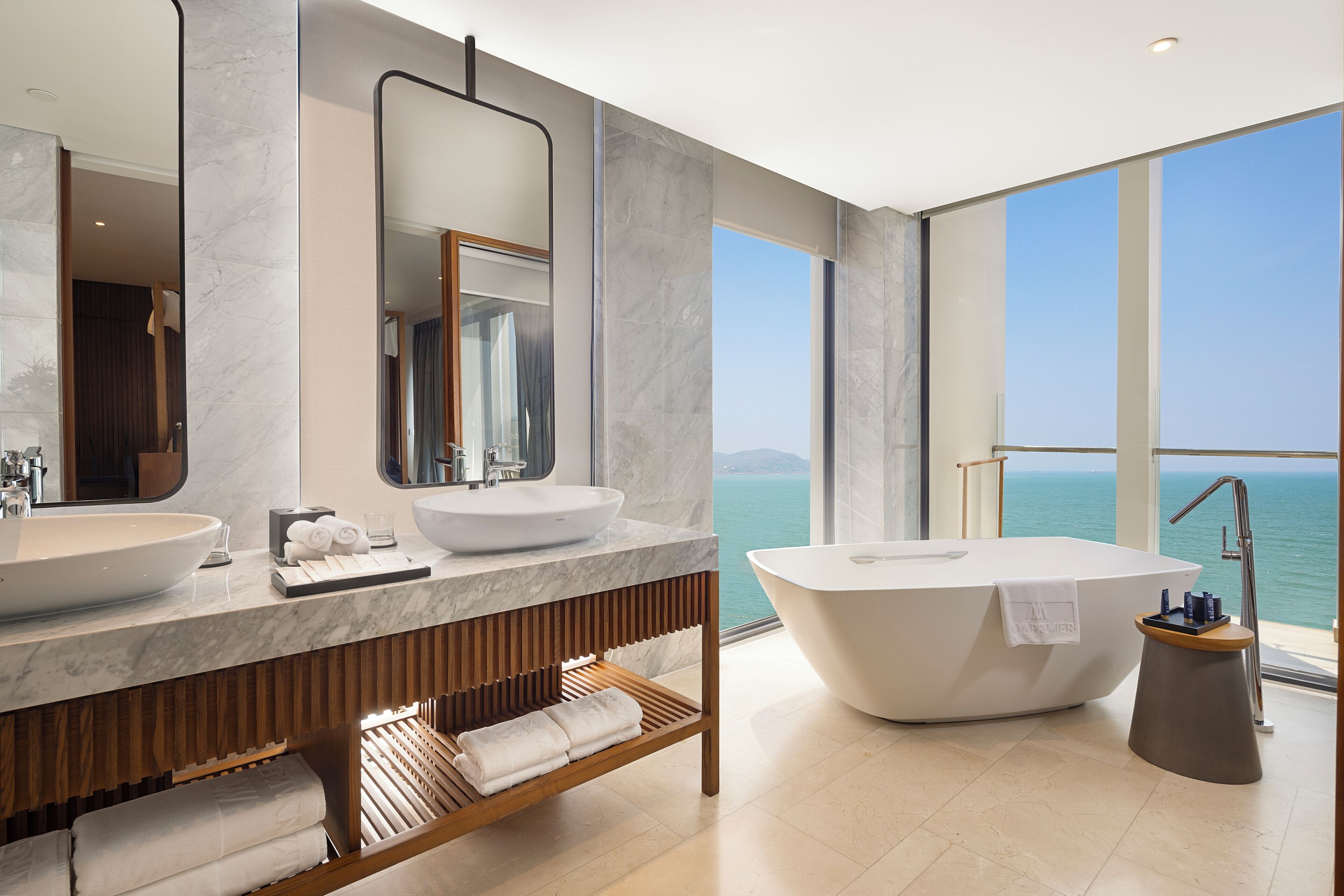 A modern bathroom with a large bathtub, two sinks, and a large mirror.