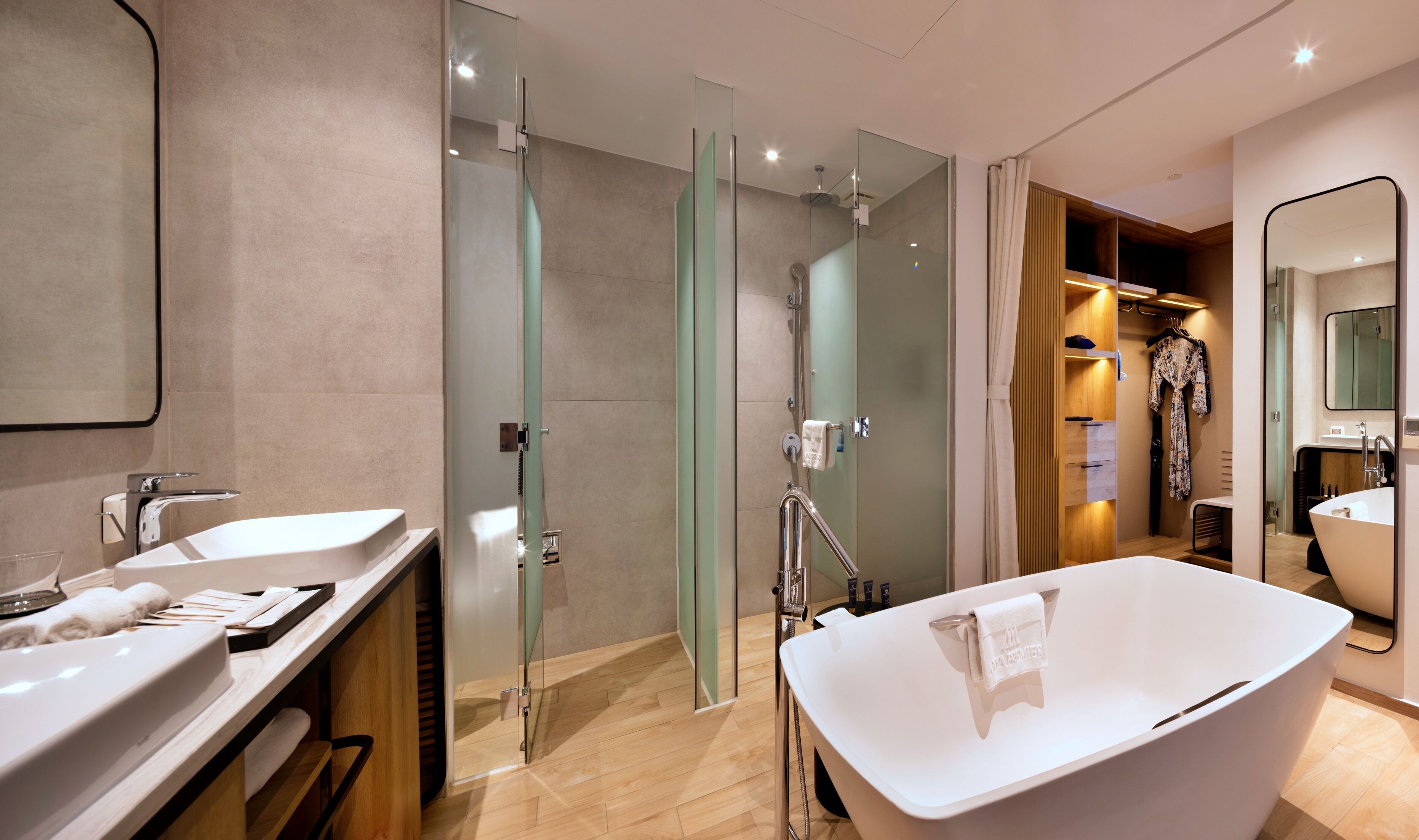 Een moderne badkamer met een vrijstaand bad, een douche met glazen wanden en een wastafel met spiegel.