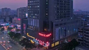 Un hotel de gran altura con varios pisos y un llamativo letrero rojo en la fachada.