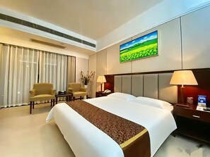 Habitación de hotel con una cama grande, dos mesitas de noche, un escritorio, una silla y una ventana con cortinas.