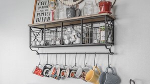 Une cuisine équipée d’un coin café, avec des tasses suspendues à un porte-tasses et une machine à café posée sur le comptoir.