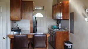 Una cocina con armarios de madera, un refrigerador, un lavamanos y un bote de basura.
