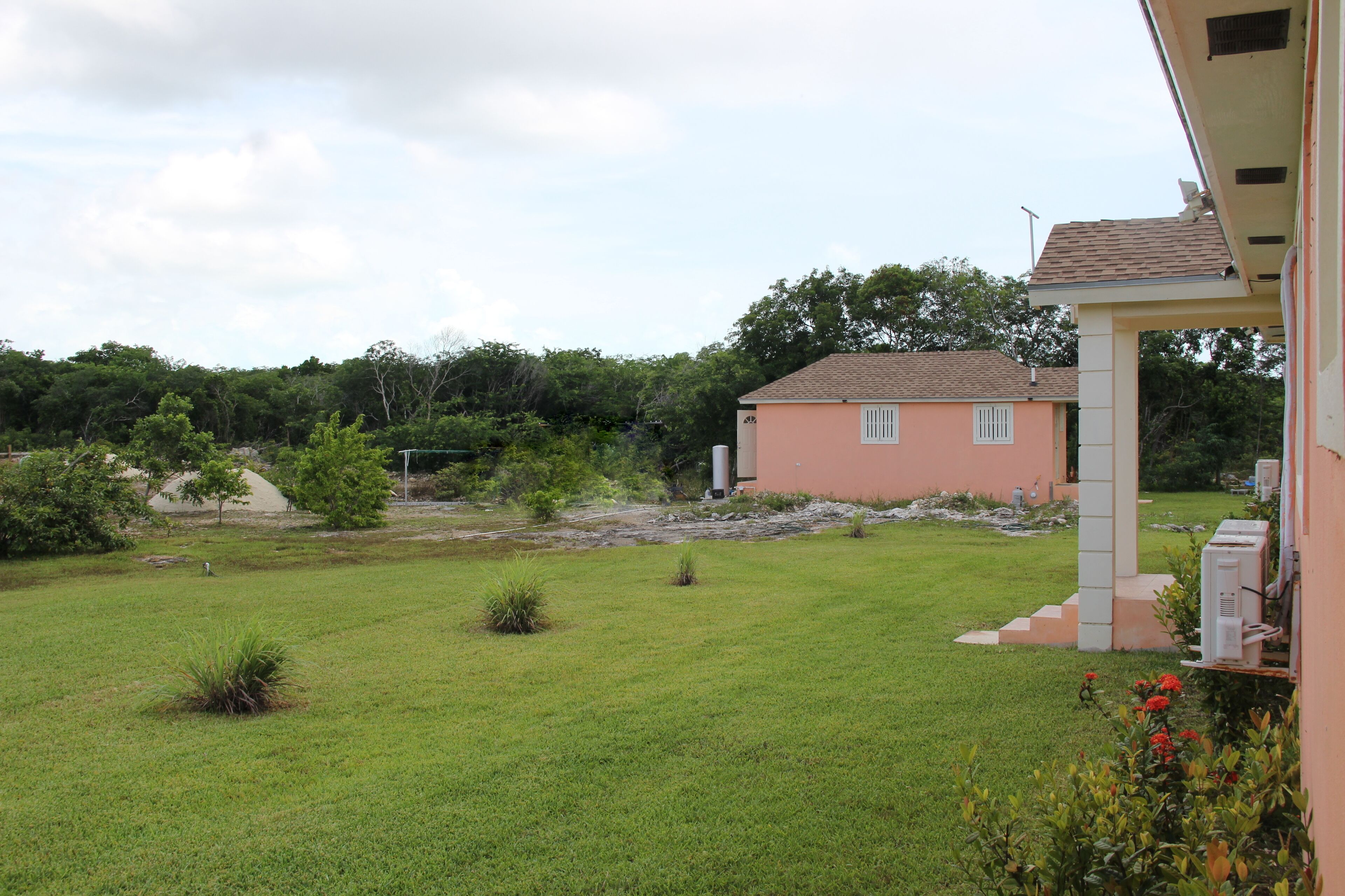 A house with a well-maintained lawn and a small garden area with red flowers.