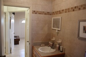 A bathroom with a sink, mirror, and tiled walls.