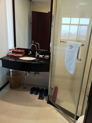 A bathroom with a black sink, a glass shower enclosure, and a towel hanging on the door.