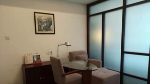 A conference room with a glass table, two chairs, a small desk, a lamp, and a framed picture on the wall. - Jiuhuashan Center Hotel (Chizhou)