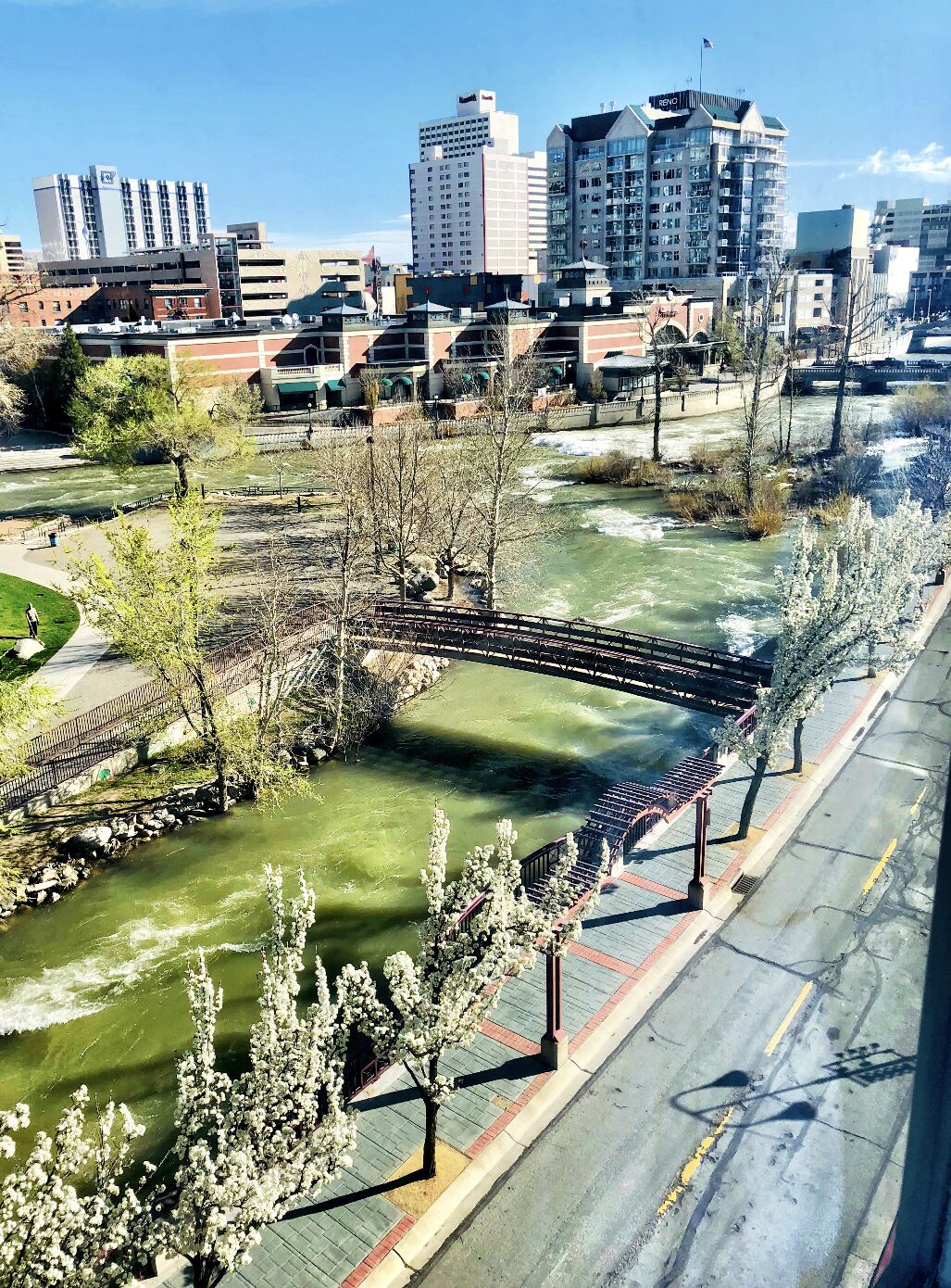 Ein Fluss mit einer Brücke, umgeben von Bäumen und Gebäuden.