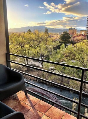 A balcony with a view of a river, trees, and distant mountains. - Stunning Views On Riverwalk Wow Factor 1BR 2BA (Reno)