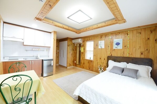 A compact room with a bed, a dining table, and a kitchenette.