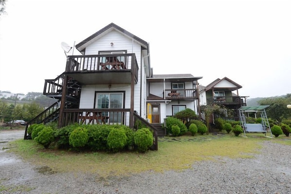 A two-story house with a balcony, a front porch, and a small garden area.
