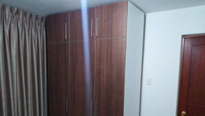 Un dormitorio con un armario grande, una cama con colcha azul y una puerta de madera.