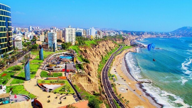 Un paisaje urbano costero con una curva destacada, una playa y una gran escultura azul.