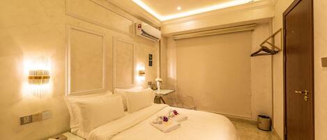 Una habitación de hotel con una cama grande, una mesita de noche y una pequeña mesa con un florero.
