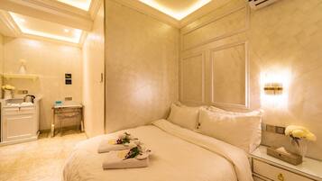 Una habitación de hotel con una cama grande, un escritorio y una mesita de noche con un jarrón de flores.