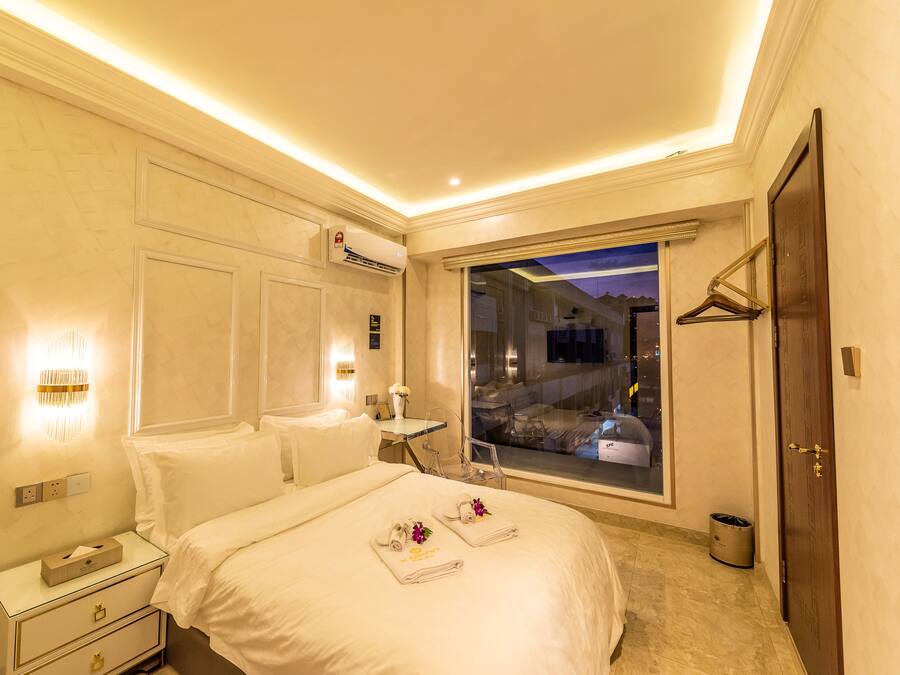 Quarto de hotel com cama, mesas de cabeceira, janela com vista e ar condicionado.