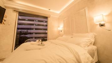 Une chambre d’hôtel avec un lit, une fenêtre avec des stores, une lampe fixée au mur et un appareil de climatisation.