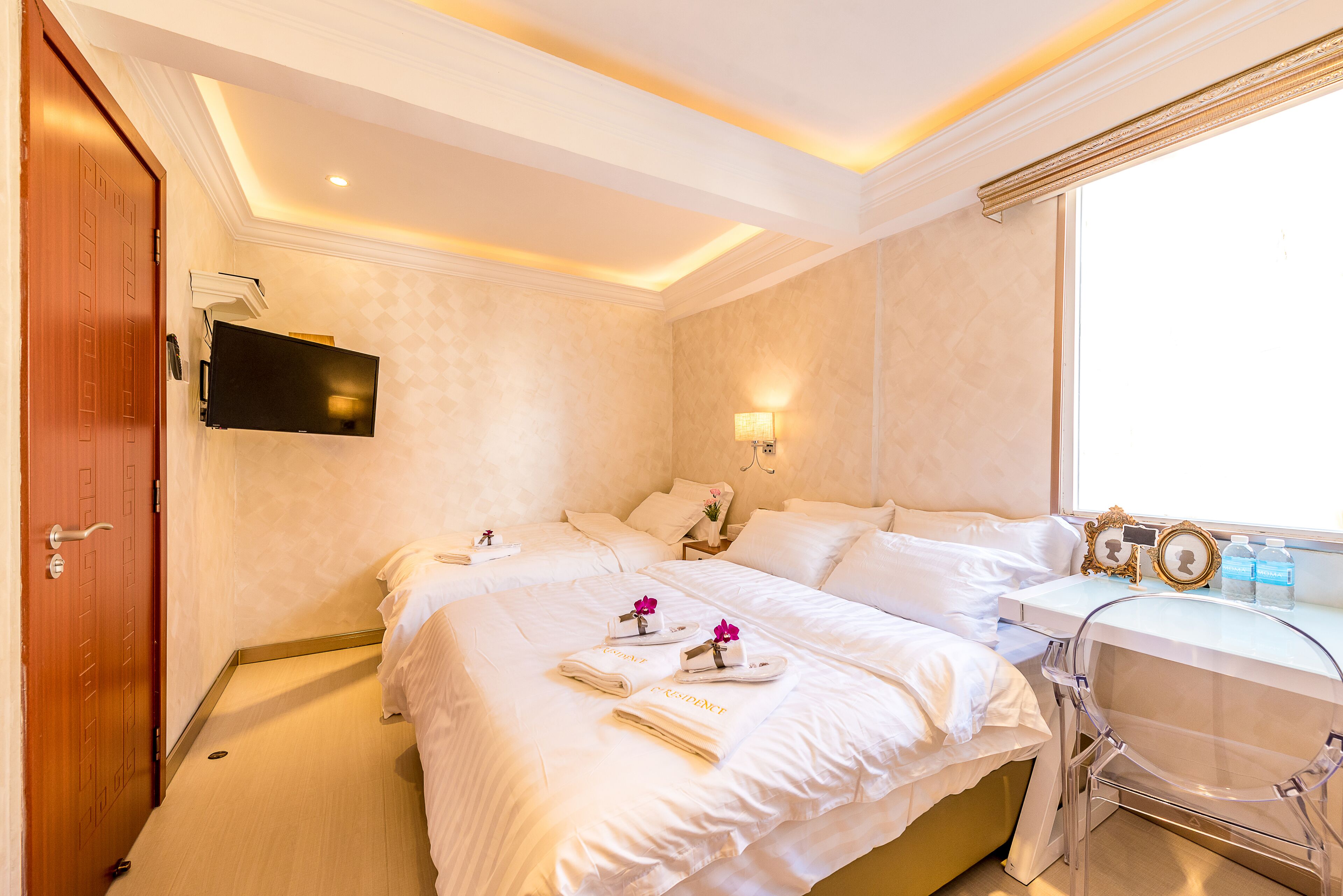 Habitación de hotel con una cama grande, un escritorio, una silla, un televisor y una ventana.