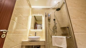 A bathroom with a marble sink, a glass-enclosed shower, and a mirror above the sink.
