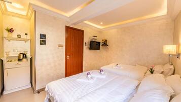Quarto de hotel com duas camas, uma porta de madeira, televisão fixada na parede e uma luminária de cabeceira.