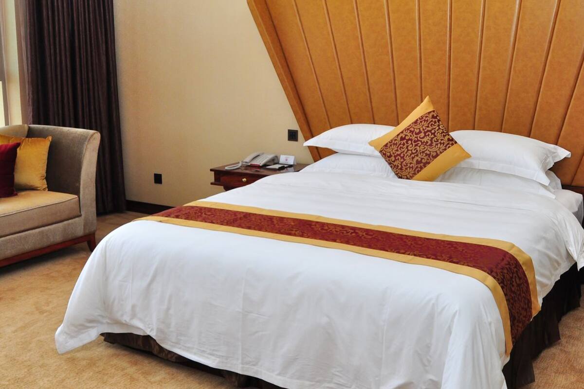 Una habitación de hotel con una cama grande, una silla, una mesita de noche y un teléfono.