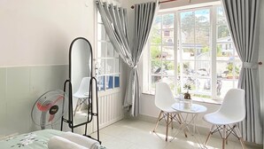 Una camera d'albergo con un letto, una sedia, un tavolo e una finestra con tende.