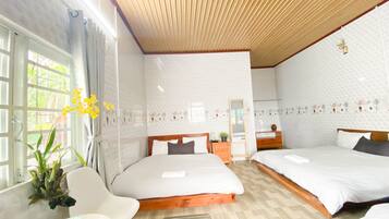 Habitación de hotel con dos camas, techo de madera y ventana con cortinas.
