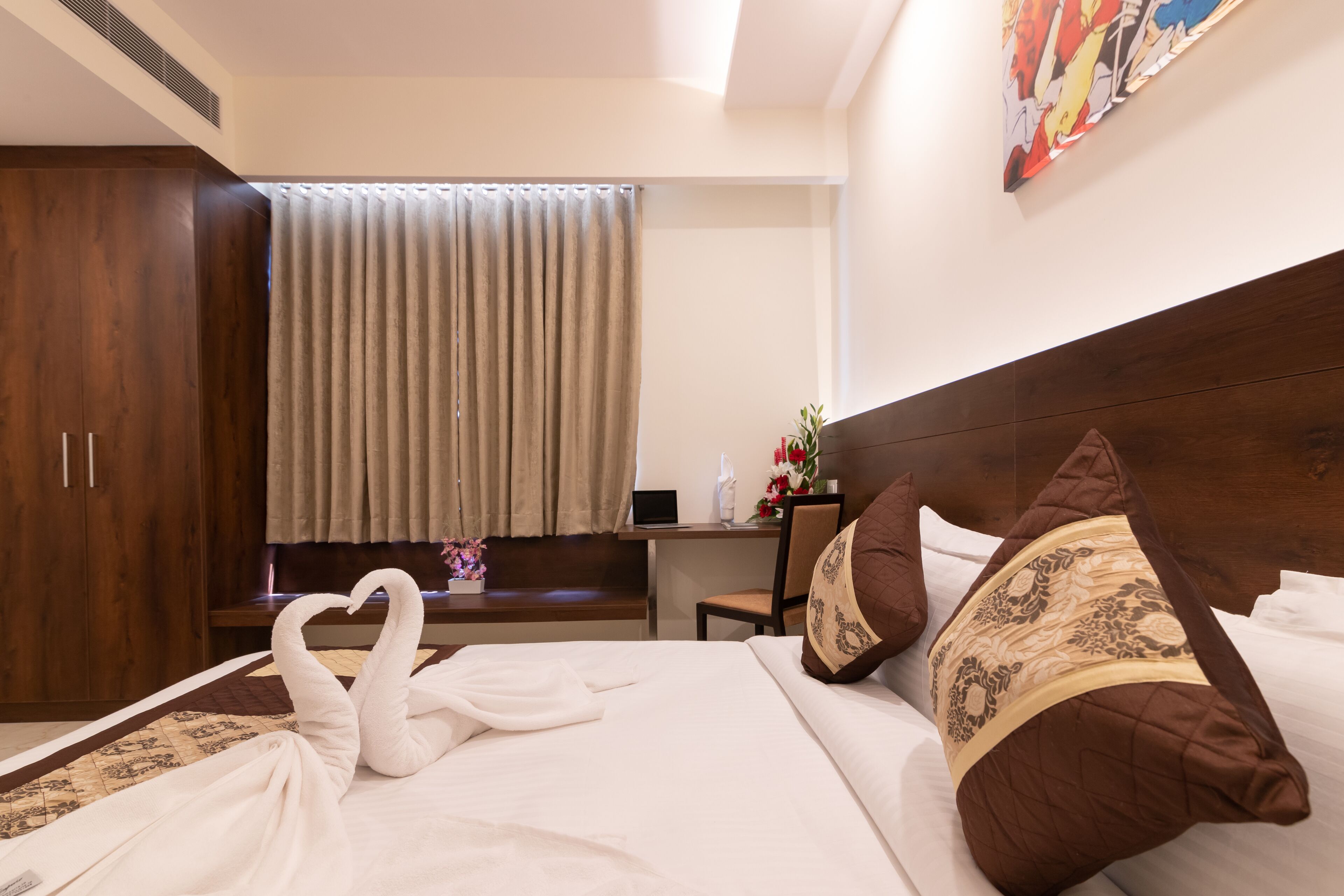 A hotel room with a bed, a desk, a chair, and a wardrobe.