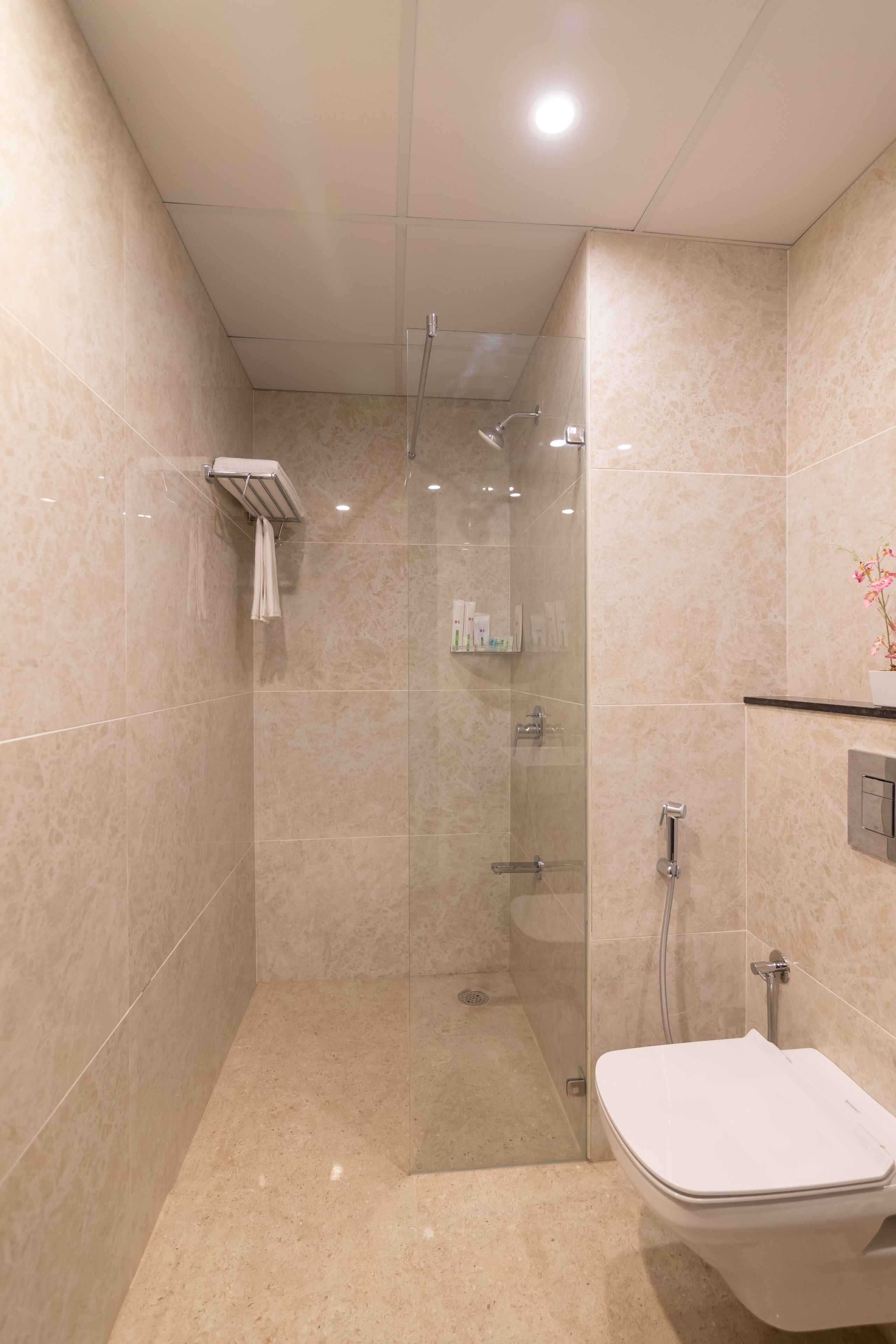 Un baño moderno con ducha envuelta en vidrio, inodoro blanco y tocador con espejo.