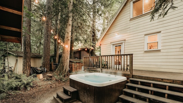 A wooden hot tub on a deck with steps, surrounded by trees and a house with a wooden deck and railing. - Mt Baker Lodging's Cabin #1 - With Wifi, Hot Tub, Pet Friendly (Deming)