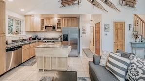 A spacious kitchen with wooden cabinets, a central island, and a dining area with a sofa and decorative pillows. - Mt Baker Lodging's Cabin #1 - With Wifi, Hot Tub, Pet Friendly (Deming)