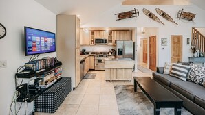 A modern kitchen with wooden cabinets, a central island, and a dining area with a sofa and coffee table. - Mt Baker Lodging's Cabin #1 - With Wifi, Hot Tub, Pet Friendly (Deming)