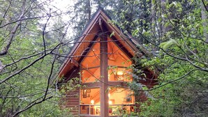 A cabin with a large window, surrounded by trees. - Snowline Cabin #4 - Pet-friendly Cedar Cabin With a Private Outdoor hot Tub! (Deming)