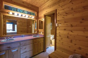 Ein Badezimmer in einer Holzhütte mit zwei Waschbecken, einem großen Spiegel und einer Toilette.