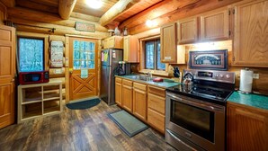 A wooden cabin kitchen with a refrigerator, stove, and wooden cabinets. - Snowline Cabin 10 - Log Cabin at its Best Free Wi-fi (Deming)