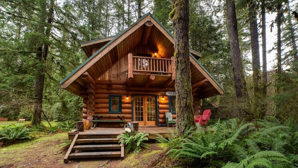 A log cabin with a balcony, surrounded by dense forest. - Snowline Cabin 10 - Log Cabin at its Best Free Wi-fi (Deming)