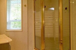 Un bagno con finestra, doccia con pareti in vetro e lavandino.